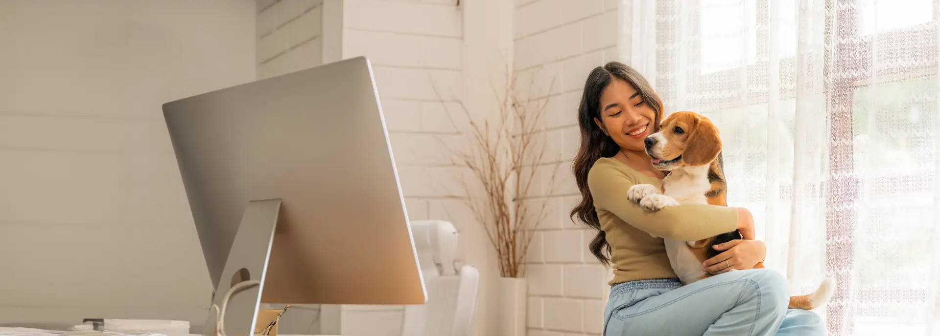 Woman in a bright, modern room hugging her beagle next to the window