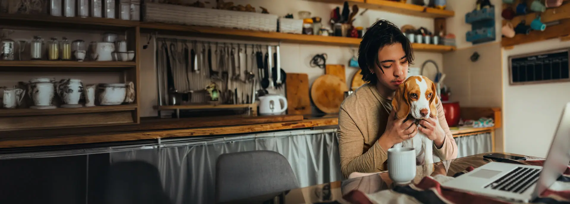 Young man in a rustic, modern kitchen sits with his dog at the table
