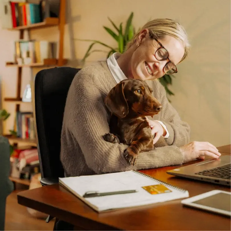 Older professional woman works from home and cuddles her dog
