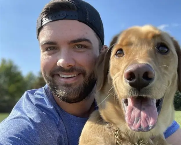 Close up of a smiling young man with a beard and his Golden Retriever